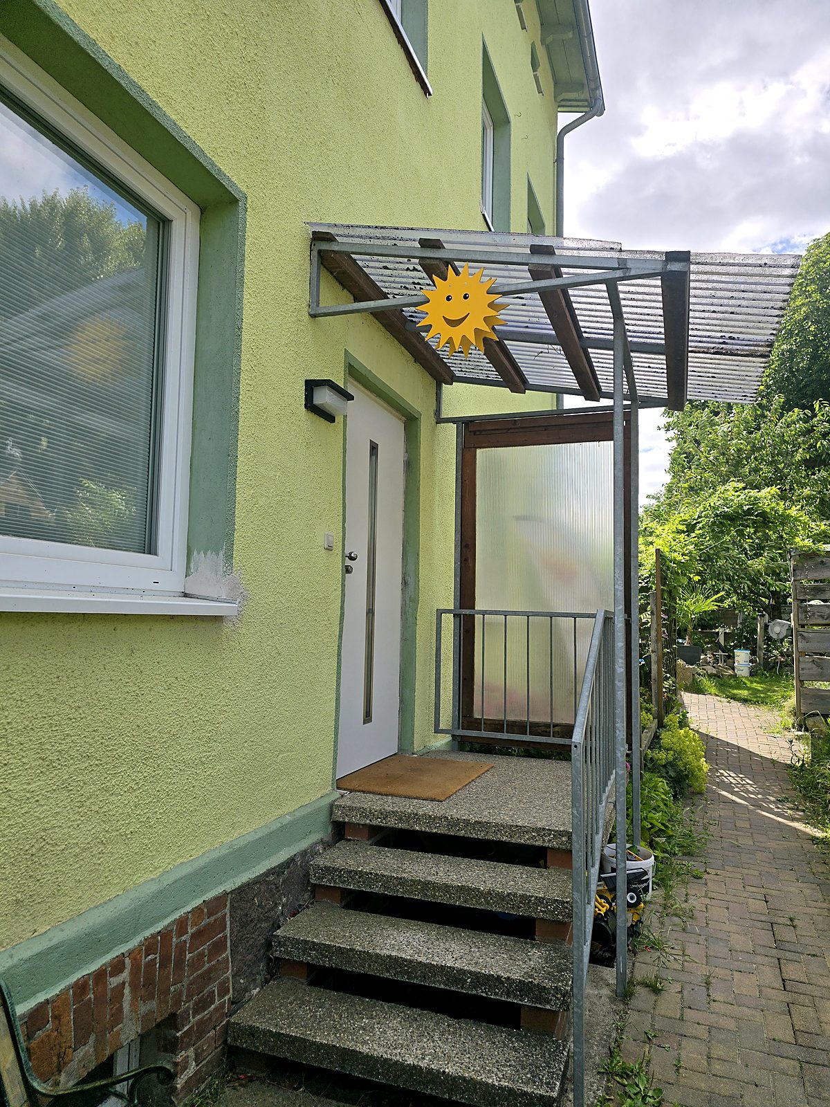 Eingang der Ferienwohnung mit überdachtem Treppenaufgang und Sonnen-Deko