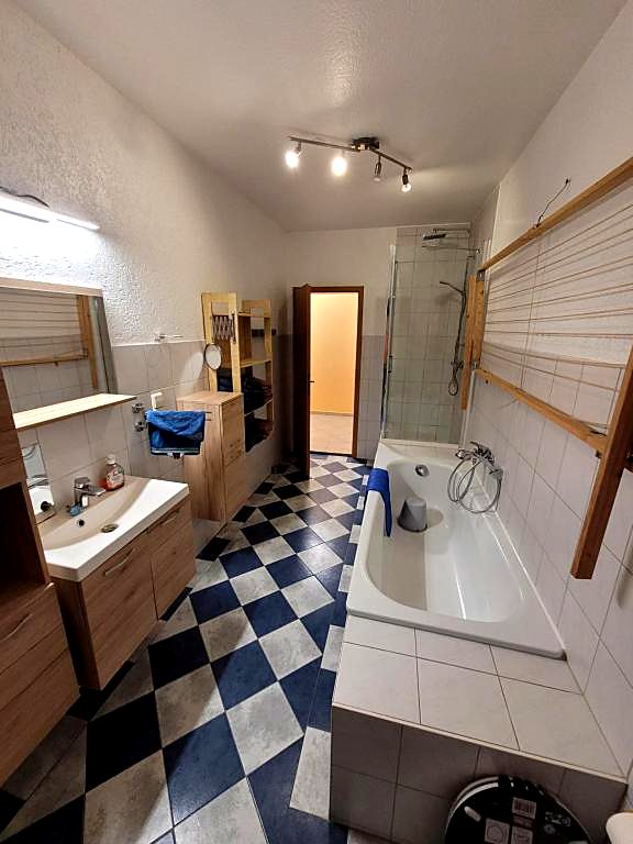 Badezimmer mit Badewanne, Waschtisch und blau-weißem Schachbrettboden